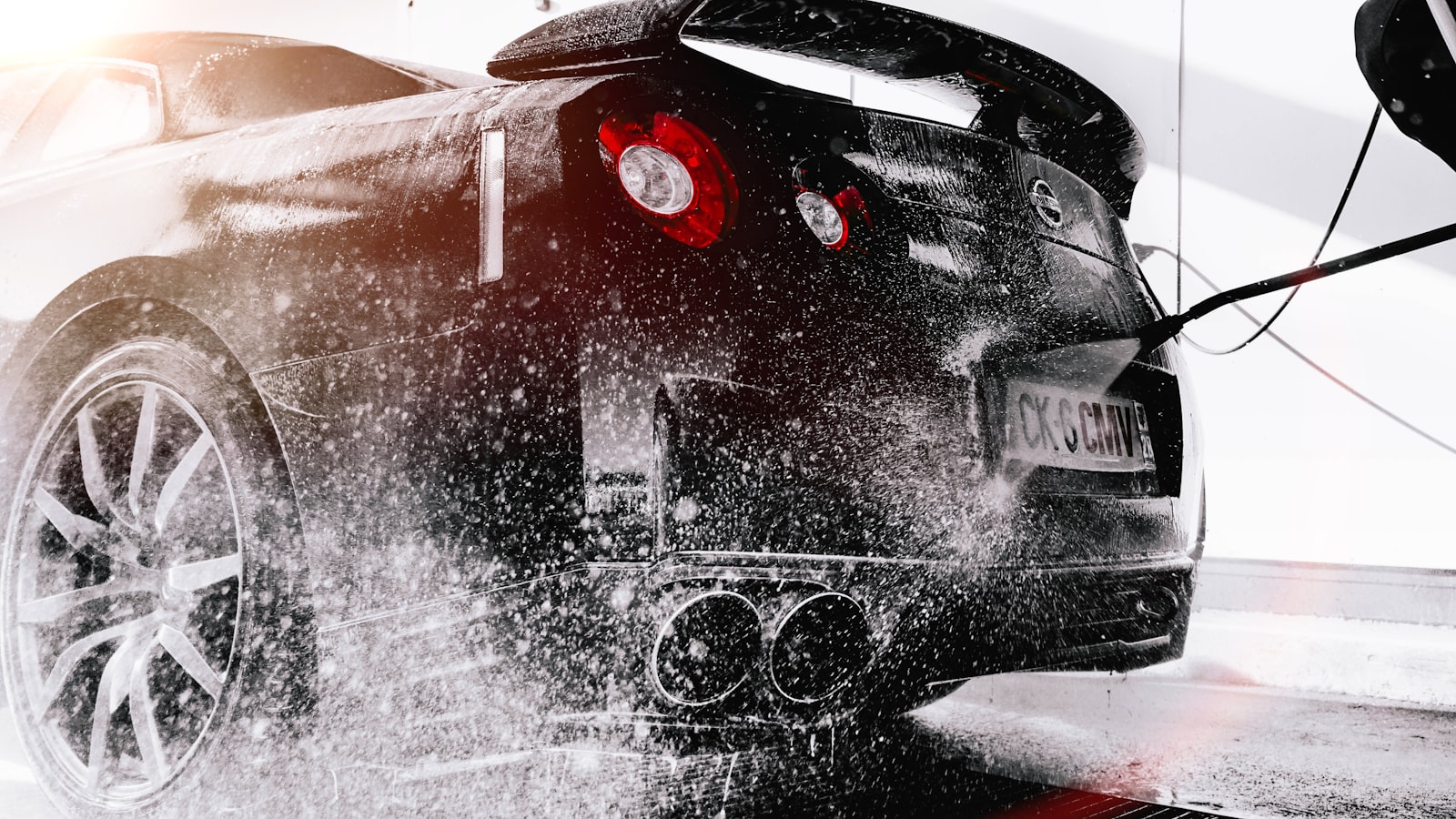 Black sports car being detailed with a pressure rinse